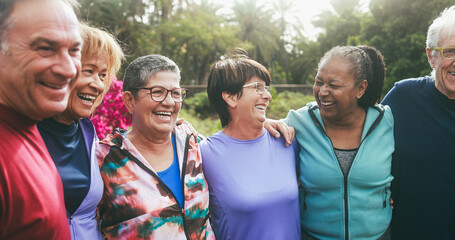 Multiracial senior people having fun hugging each other after sport workout at city park - Healthy lifestyle and joyful elderly lifestyle concept
