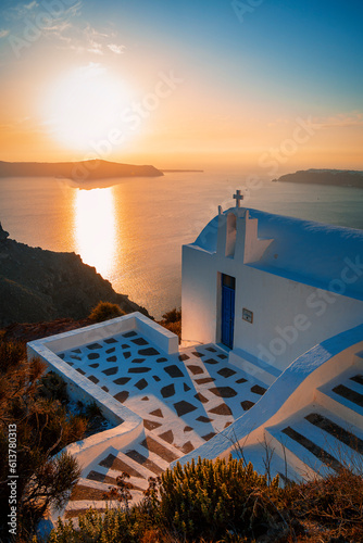 Sunset over small white chapel overlooking the sea and islands on the Greek island of Santorini