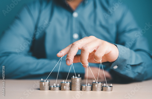 Businessman or Puppeteer hand controlling stacked coins. World economic conspiracy, global financial control and manipulation concept. Business investment, Stock market, Inflation, and Future trading.