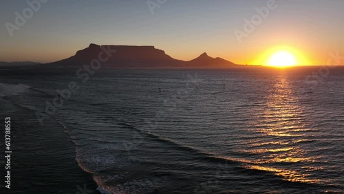 Cape Town South Africa windsurfers sailing windy surf wave Table Mountain drone aerial cinematic Lions Head sunset beach stunning mountain and ocean landscape orange gold sun on horizon backward pan