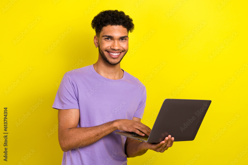 Photo of young man hold netbook online corporate meeting wear purple t-shirt use laptop order clothes isolated on yellow color background Photo of young man hold netbook online corporate meeting wear purple t-shirt use laptop order clothes isolated on yellow color background