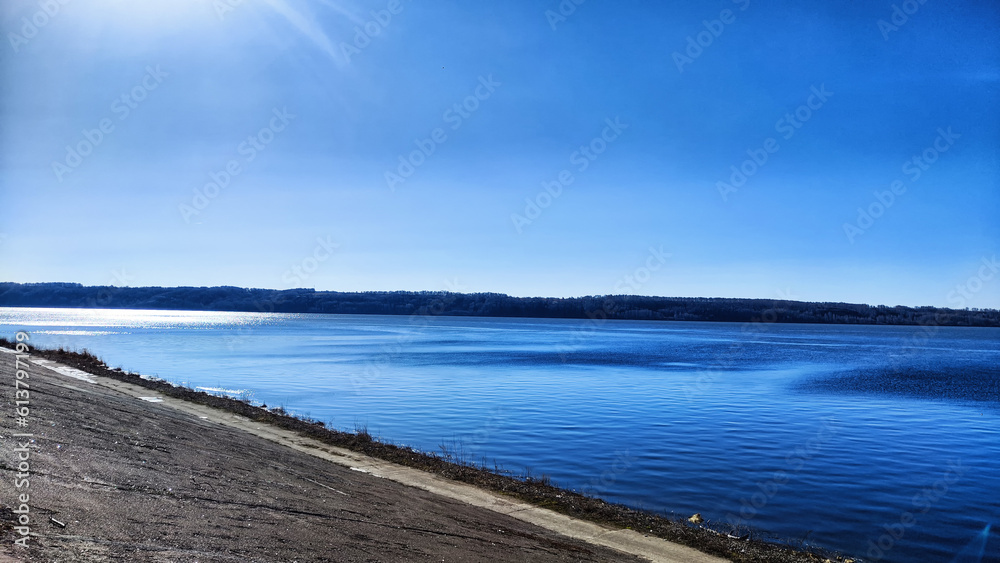 Beautiful blue water, sky and earth on the distant horizon. Natural landscape with water on a sunny day. Background with landscape and copy space