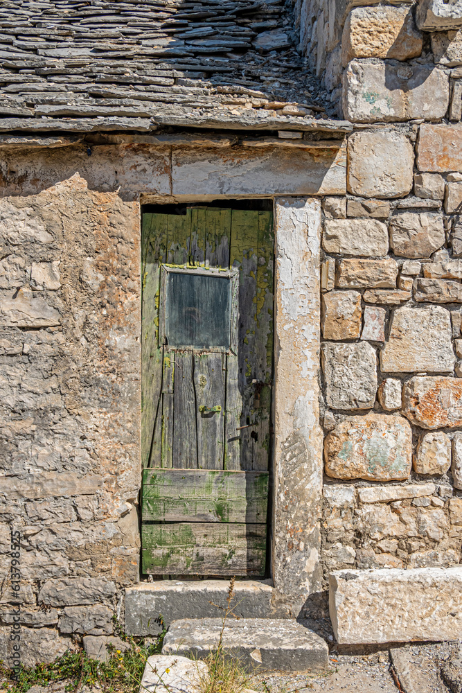 Typical old house with weathered doors and stone wall, Rogoznica village, Dalmatia, Croatia Typical old house with weathered doors and stone wall, Rogoznica village, Dalmatia, Croatia