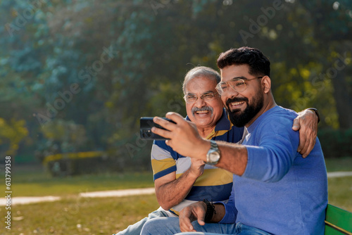 Young man taking selfie with his father at park