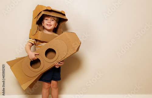 Boy holds homemade cardboard rocket, imagines space voyage