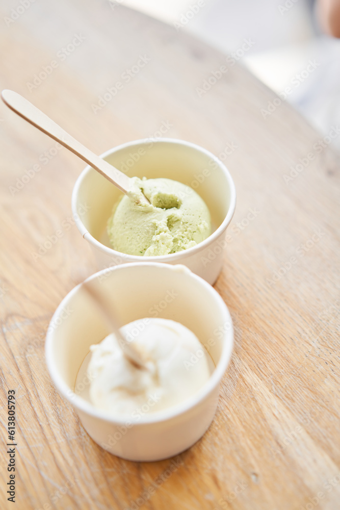 Vanilla and pistachio ice-cream. Ice cream in two disposable cups on the table. Italian gelateria. Natural fresh gelato. Vanilla and pistachio ice-cream. Ice cream in two disposable cups on the table. Italian gelateria. Natural fresh gelato.