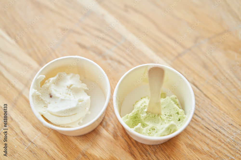 Vanilla and pistachio ice-cream. Ice cream in two disposable cups on the table. Italian gelateria. Natural fresh gelato. Vanilla and pistachio ice-cream. Ice cream in two disposable cups on the table. Italian gelateria. Natural fresh gelato.