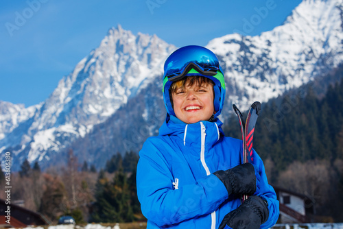 Laughing child stand over mountains with ski mask and helmet