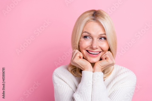 Portrait of optimistic retired person blond hair wear white sweater look empty space arm on cheeks isolated on pink color background