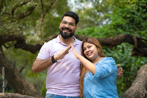 Young indian couple making home shape with hand at park