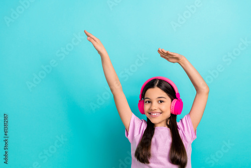 Photo of brunette hair preteen girl music sound earphones raised hands up vibe kids entertainment isolated on aquamarine color background © deagreez