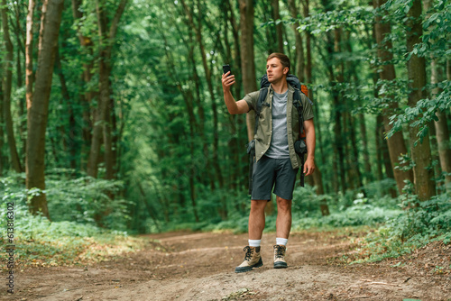With smartphone in hands. Tourist in summer forest. Conception of exploration and leisure