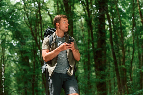 Searching the way, with smartphone for navigation. Tourist in summer forest. Conception of exploration and leisure