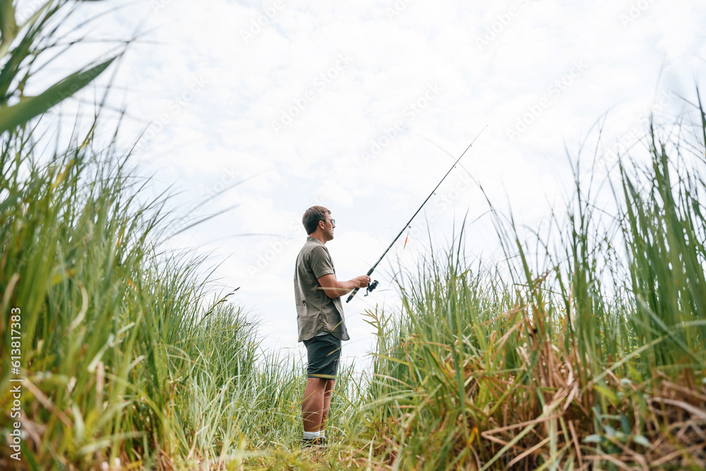 Handsome man in sunglasses is fishing outdoors