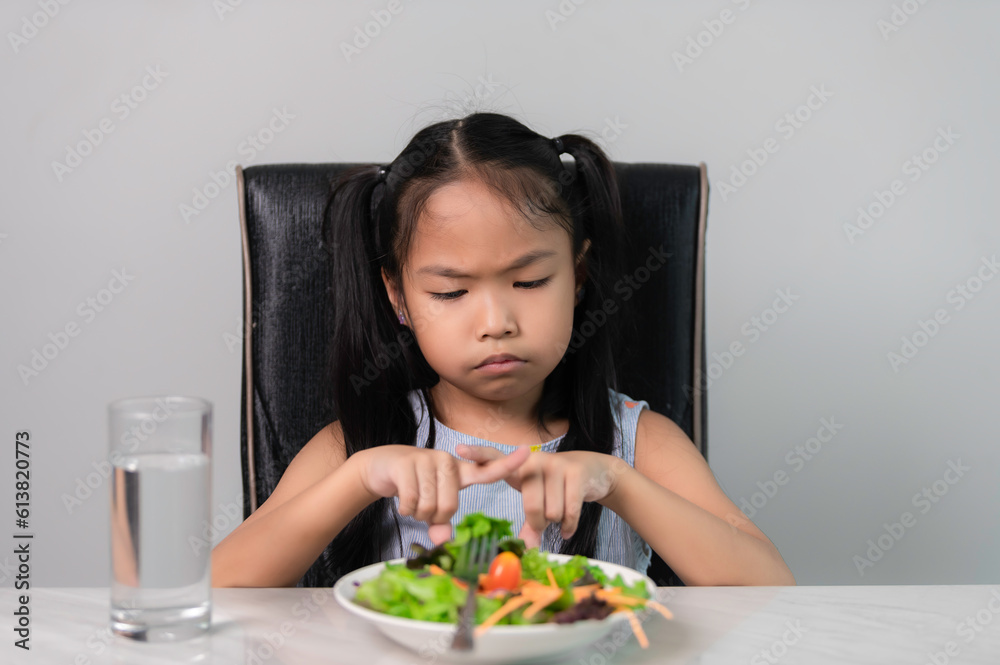 Little asian cute girl refuses to eat healthy vegetables.Nutrition & healthy eating habits for kids concept.Children do not like to eat vegetables. Little asian cute girl refuses to eat healthy vegetables.Nutrition & healthy eating habits for kids concept.Children do not like to eat vegetables.