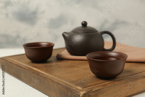 Cups of aromatic tea and teapot on white table