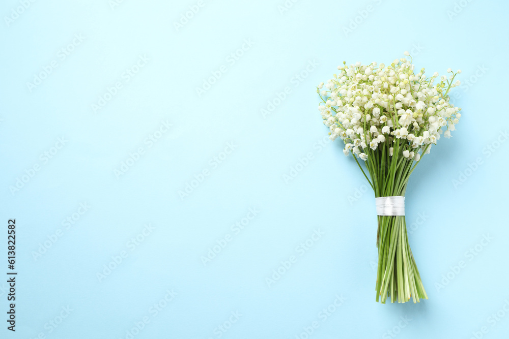 Beautiful lily of the valley bouquet on light blue background, top view. Space for text Beautiful lily of the valley bouquet on light blue background, top view. Space for text