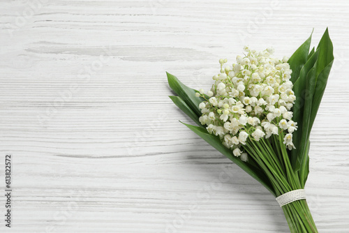 Beautiful lily of the valley bouquet on white wooden table  top view. Space for text