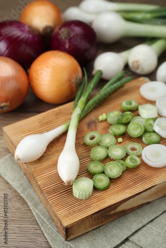 Different kinds of onions on wooden table, closeup