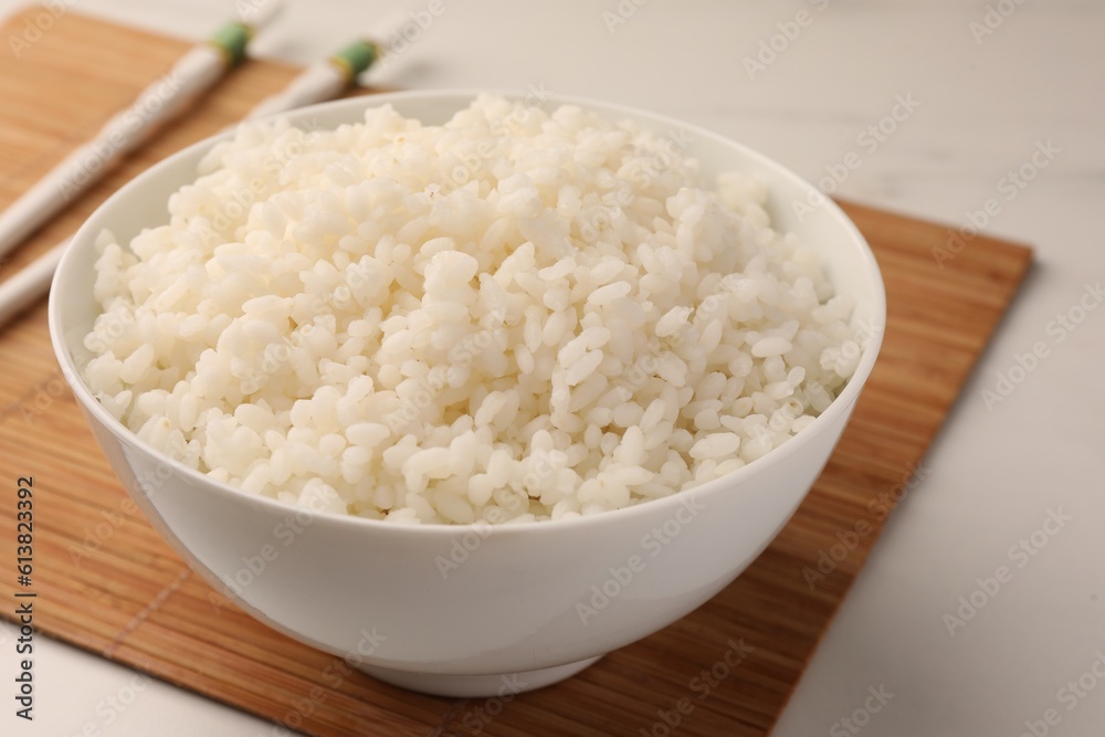 Bowl with delicious rice and chopsticks on white table, closeup Bowl with delicious rice and chopsticks on white table, closeup