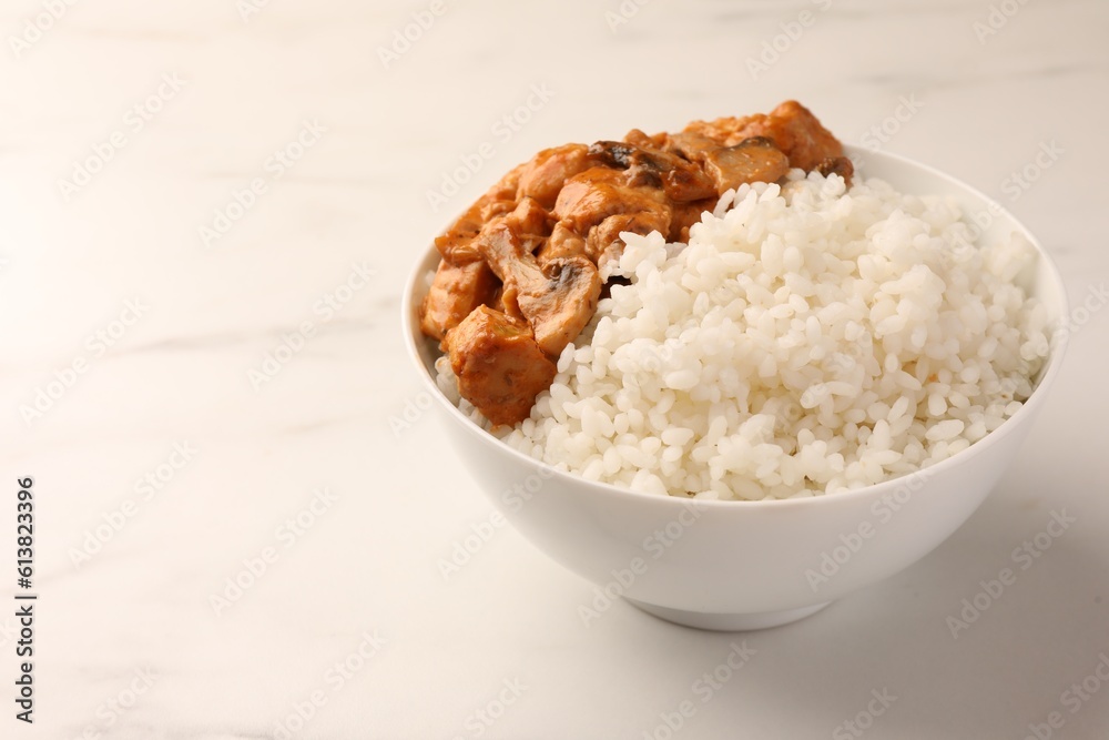 Bowl of delicious rice with meat and mushrooms on white marble table, space for text Bowl of delicious rice with meat and mushrooms on white marble table, space for text