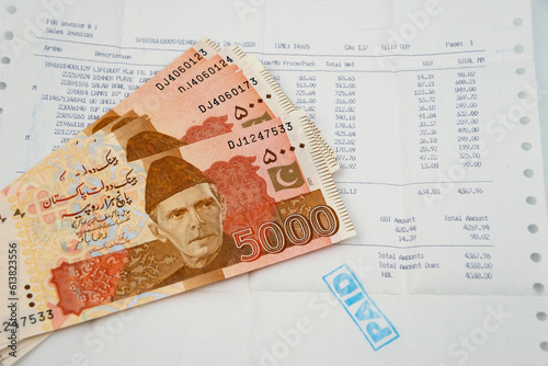 Currency notes in Pakistani Rupees with a paid invoice.