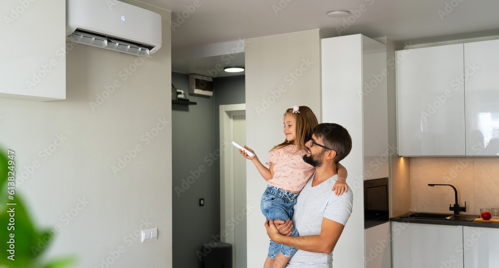 Father kept to hand little girl and turn on air conditioner using remote control. Happy family adjust comfortable temperature of cooler system Father kept to hand little girl and turn on air conditioner using remote control. Happy family adjust comfortable temperature of cooler system