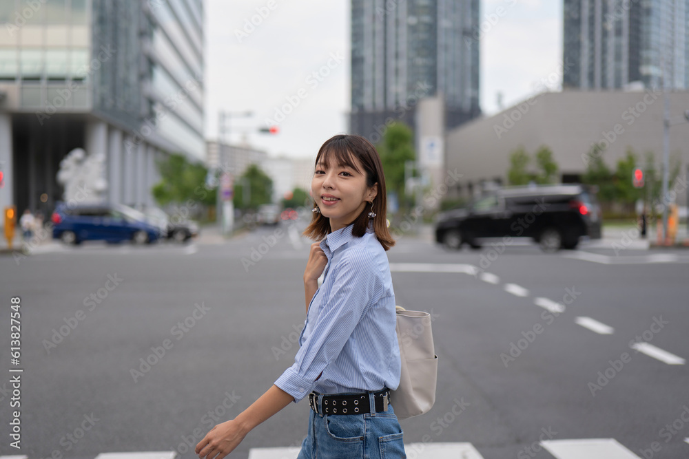 Fototapeta premium ビジネス街の横断歩道を渡る笑顔のビジネスウーマン