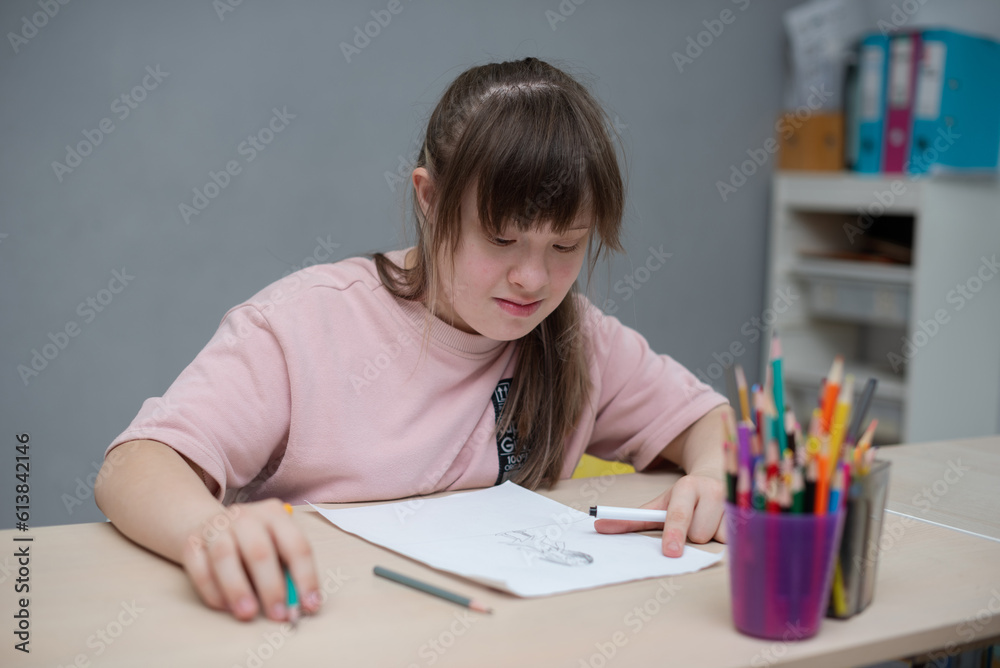 Sunny girl painting in art class at school. World day of people with down syndrome Sunny girl painting in art class at school. World day of people with down syndrome