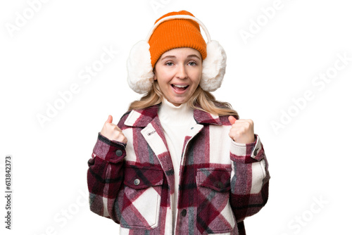 Young English woman wearing winter muffs over isolated background celebrating a victory in winner position