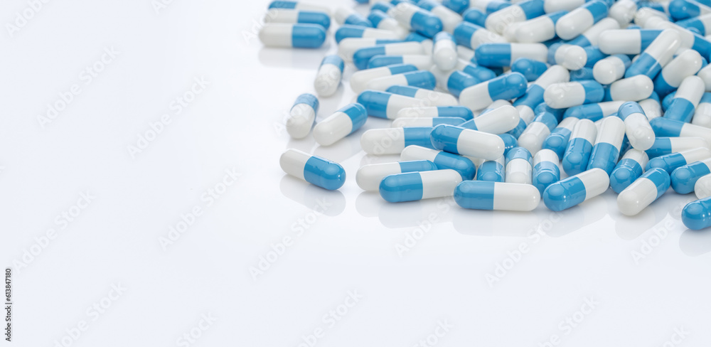 Blue-white antibiotic capsule pills on white background. Pile of antibiotic drug. Antibiotic drug resistance. Prescription drugs. Healthcare and medicine. Pharmaceutical industry. Pharmacy product. Blue-white antibiotic capsule pills on white background. Pile of antibiotic drug. Antibiotic drug resistance. Prescription drugs. Healthcare and medicine. Pharmaceutical industry. Pharmacy product.