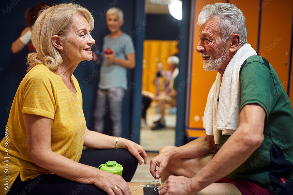 Senior man and woman in sportswear sitting in dressing room talking, cheering each other up for workout. Senior man and woman in sportswear sitting in dressing room talking, cheering each other up for workout.