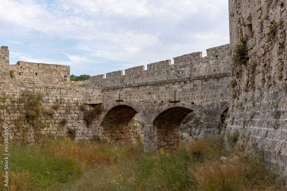 Stone wall fortifications and arch bridges in moat of old town of Rhodes, Greece