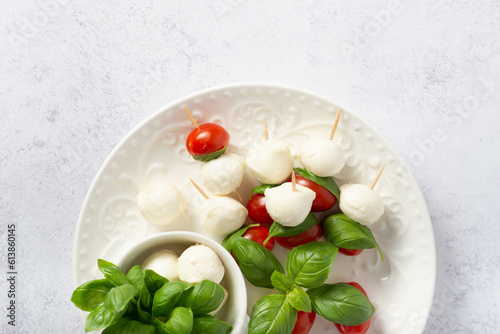 Mozzarella cheese balls, tomatoes, basil leaves and peppercorns for caprese salad flying on white background.