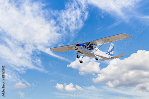 Single engine ultralight plane flying in the blue sky with white clouds 