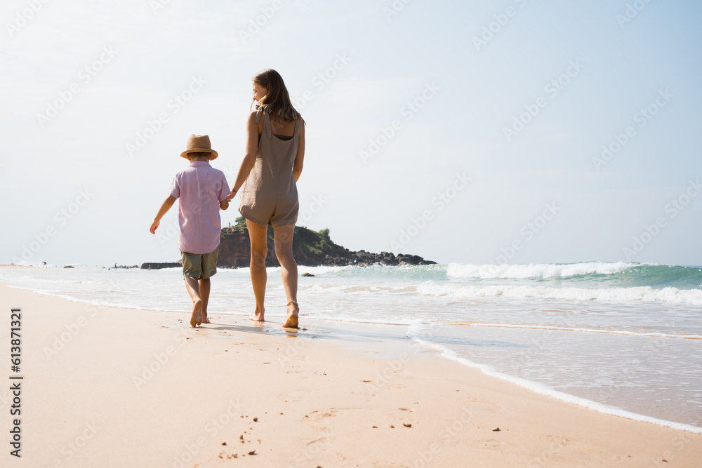 barefoot mother with child walking on sea cost