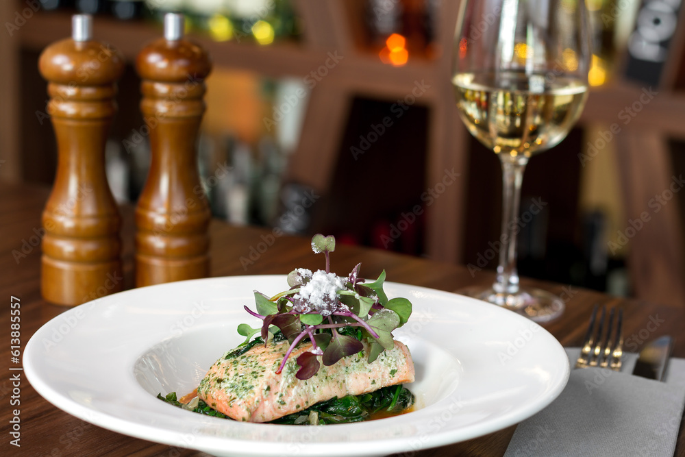 a white plate topped with a piece of grilled chicken food next to a glass of wine