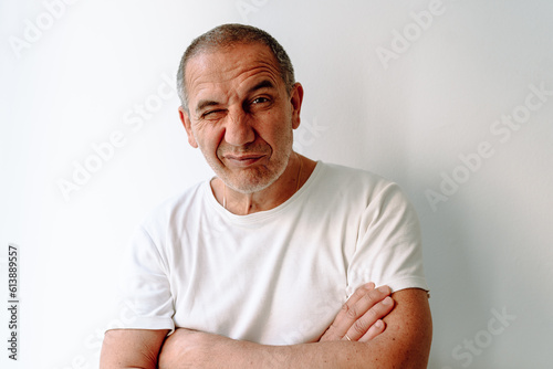 Portrait middle-aged man in white t-shirt with grimace on face on white background