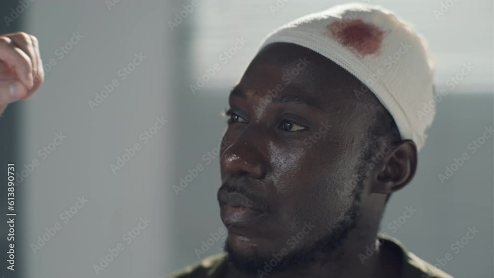 Close-up of doctor using flashlight to examine eysight of soldier with wound on head in hospital