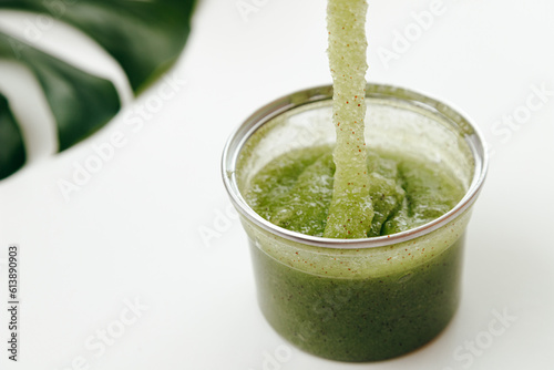 Green Natural Organic Polish Exfoliator Scrub Flows into a Jar on White background