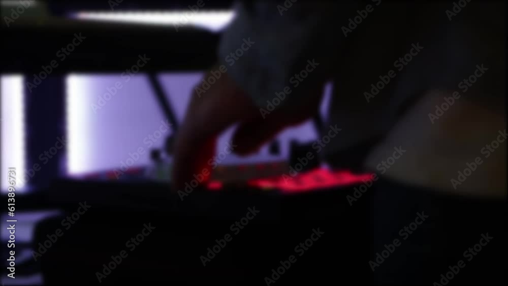 A DJ adjusts the equalizer and volume settings on a DJ console in a nightclub, close-up. Blurry A DJ adjusts the equalizer and volume settings on a DJ console in a nightclub, close-up. Blurry