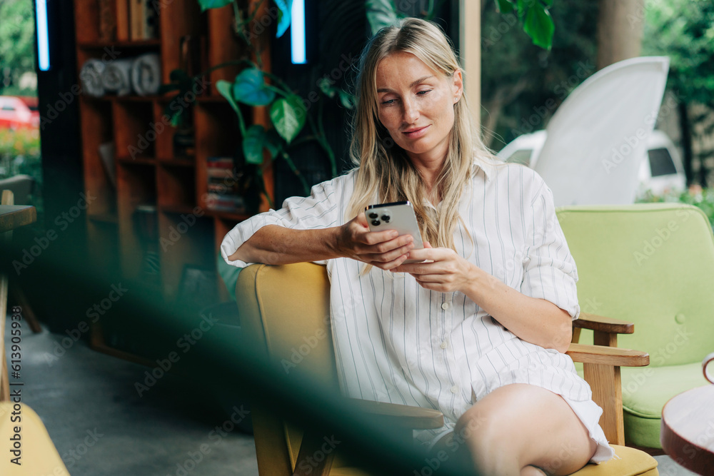 © Ilona - Young modern woman scrolling social media and messages in mobile phone. © Ilona - Young modern woman scrolling social media and messages in mobile phone.