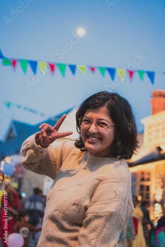 Pretty Indian girl smiling while looking at camera making victory sign - Cute India girl with glasses smiling