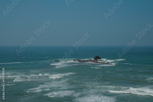 Aerial view of Atlantic Ocean from Legzira Beach. Rocky island in the middle of wild waves. Landmark in Tiznit Province of Morocco, Africa. Travel background. Summer day. Rugged vacation escape. © pam