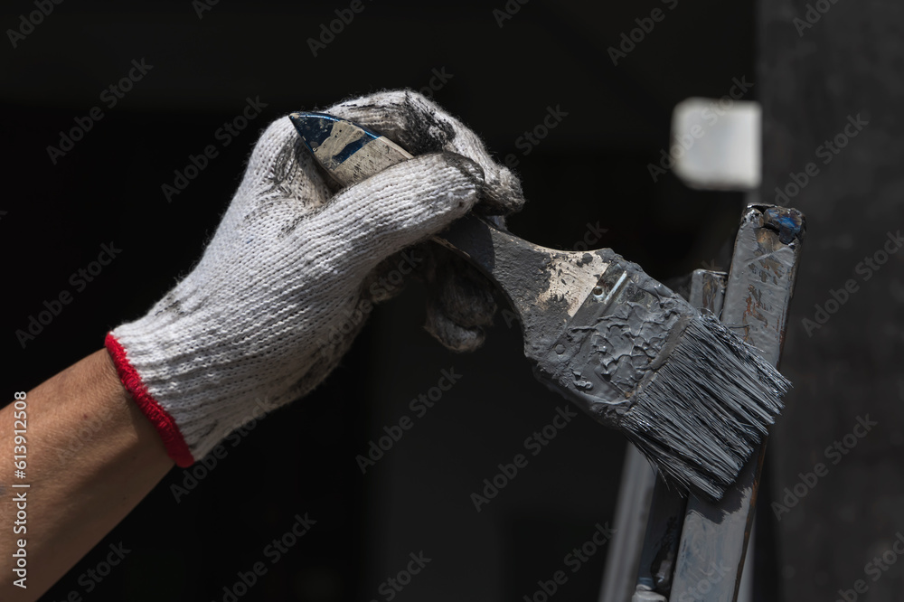 Close up painter hand wearing glove holding paintbrush doing steel painting in construction site , Home Improvment