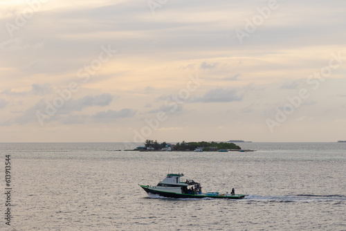 Fishing boat or boats are in the midst of the sea on a beautiful blue sky with sky and island in the background © Coverage Studio