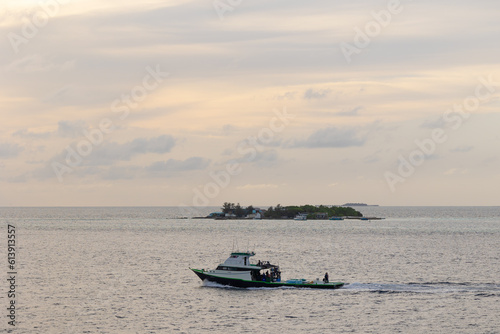 Fishing boat or boats are in the midst of the sea on a beautiful blue sky with sky and island in the background