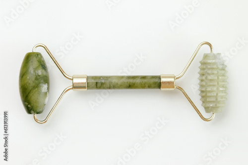 Facial jade massage roller made of green quartz stone on white background.