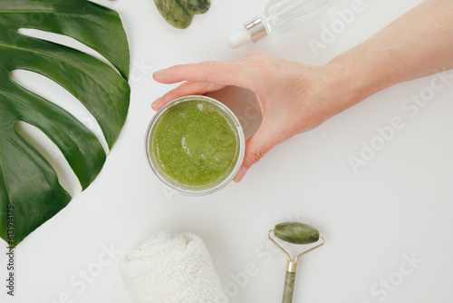 Woman Taking Jar with Cosmetics Green Natural Scrub, white background, top view