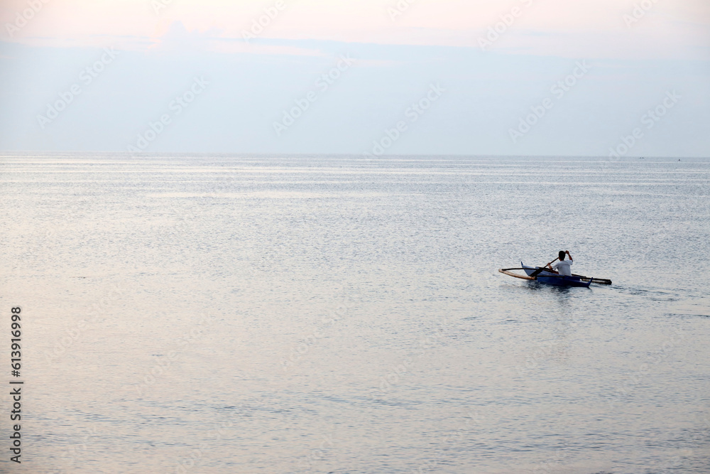 Fototapeta premium lonely boat at sunrise or sunset in the ocean in a tropical country, seascape